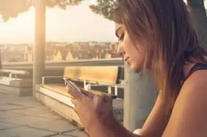 Une femme utilisant son téléphone sur un banc.