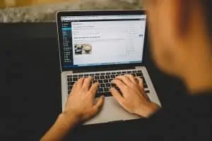 Un homme tapant sur un ordinateur portable avec une tasse de café dessus, démontrant l'importance des blogs pour le référencement.