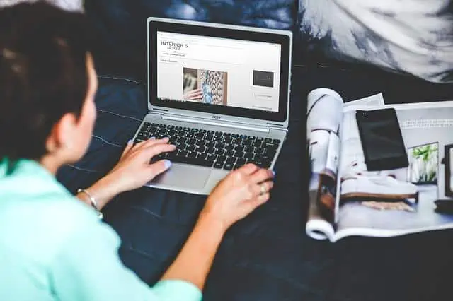 Une femme utilisant un ordinateur portable sur un lit tout en bloguant pour son entreprise.