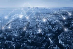 Vue aérienne d'une ville avec des lignes numériques blanches et des points illustrant la connectivité du réseau, montrant comment une agence de communication ou un travailleur autonome peut rester connecté à différents endroits.